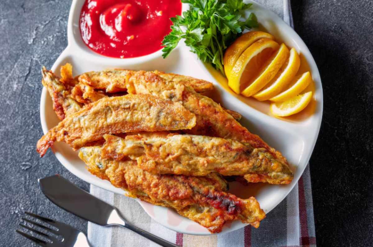 A plate of crispy fried fish coated with Hillbilly Fish Fry Seasonings, served with Southern sides like coleslaw and hushpuppies for a delicious meal.