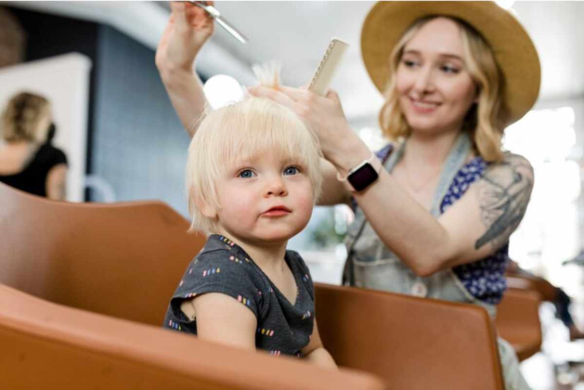 Happy baby enjoying a gentle haircut and pampering at a Salon Baby Event, with soothing treatments like facials and massages using baby-safe products in a calm, welcoming setting.