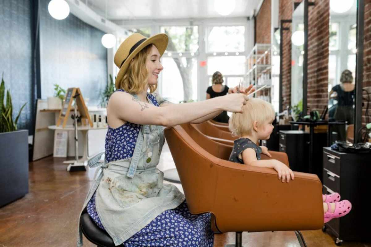 Baby enjoying a gentle haircut and pampering at a Salon Baby Event, with soothing treatments like facials and massages in a calm, baby-friendly environment.
