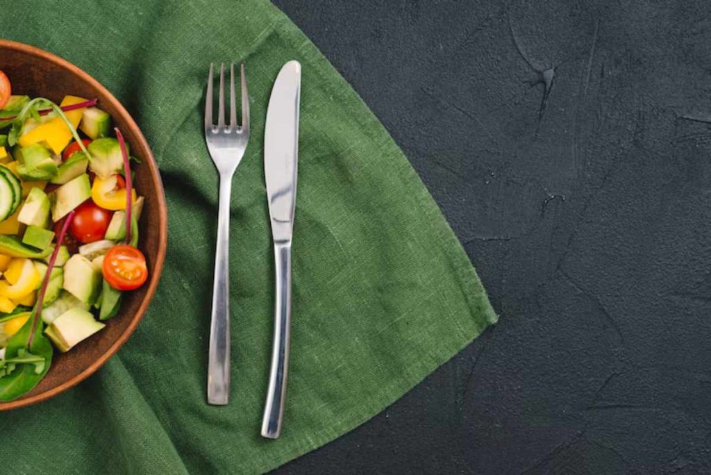 "Set of elegant salad forks arranged beside a fresh green salad"