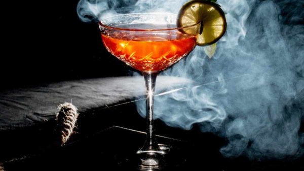 "Smoked Old Fashioned cocktail with orange peel garnish and smoke swirling in a glass"