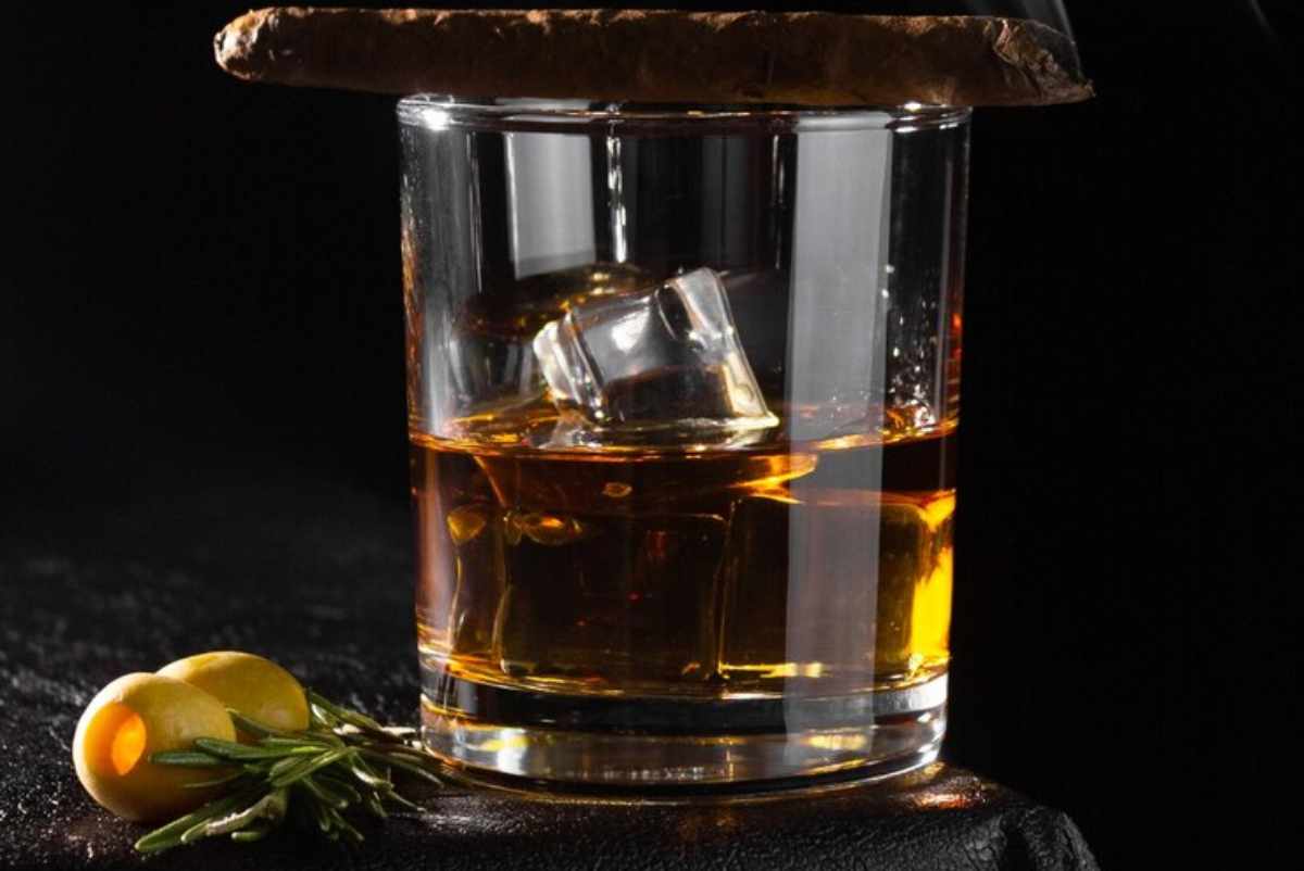 "Ingredients for a Smoked Old Fashioned drink laid out on a wooden table"